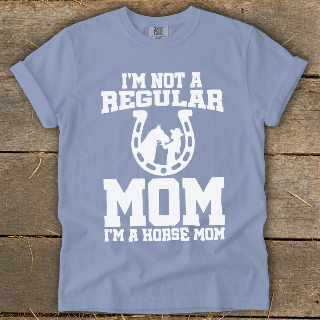 Light blue t-shirt with white text and a horse and rider silhouette within a horseshoe.