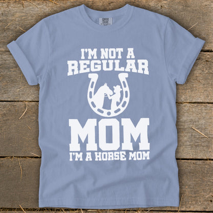 Light blue t-shirt with white text and a horse and rider silhouette within a horseshoe.