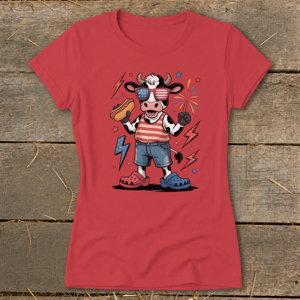 Cartoon cow in sunglasses holding hot dog and sparkler, wearing striped shirt and denim shorts.