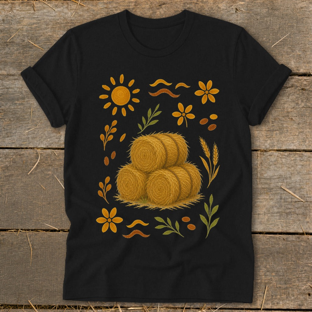 Black t-shirt with a graphic featuring three hay bales surrounded by sunflowers and wheat stalks.