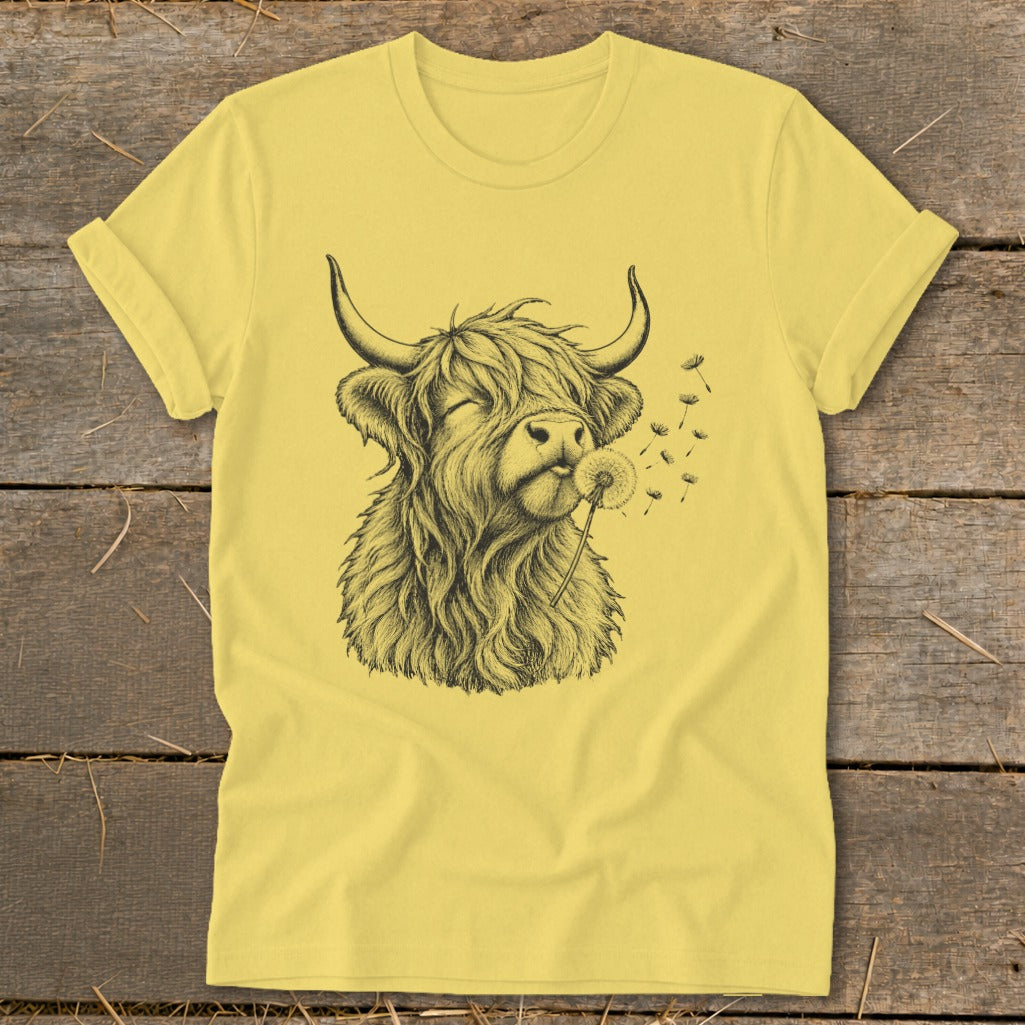 Yellow t-shirt with a black ink sketch of a Highland cow blowing a dandelion.