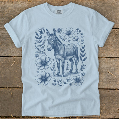 Light blue t-shirt with a navy blue donkey illustration surrounded by flowers.