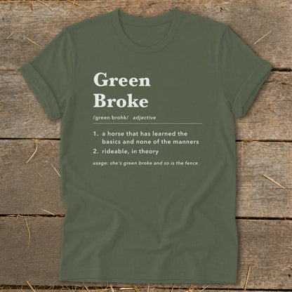 Olive green t-shirt with white text defining Green Broke laid flat on wooden boards.