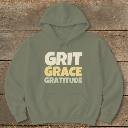 An olive green hooded sweatshirt with a front pocket, printed with the words Grit, Grace, Gratitude.