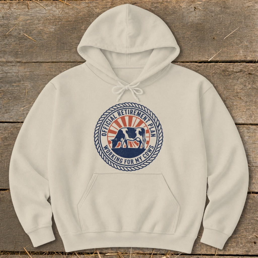 Cream hoodie with a circular graphic featuring a cow and the text "Official Retirement Plan Working For My Cows."