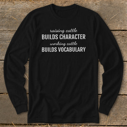 Black long sleeve shirt with white text reading "raising cattle BUILDS CHARACTER working cattle BUILDS VOCABULARY".