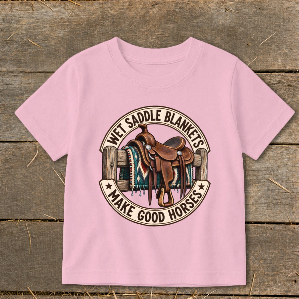 Pink t-shirt graphic with saddle, blanket, fence, and text "Wet Saddle Blankets Make Good Horses".