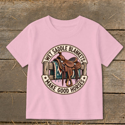 Pink t-shirt graphic with saddle, blanket, fence, and text "Wet Saddle Blankets Make Good Horses".