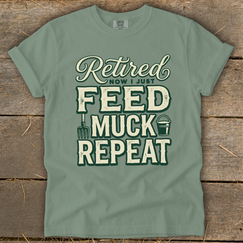 "Retired Now I Just Feed Muck Repeat" graphic t-shirt with fork and bucket.