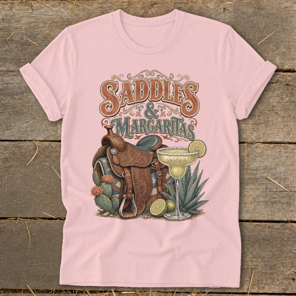 Pink t-shirt with "Saddles & Margaritas" text, saddle, margarita, and cacti.