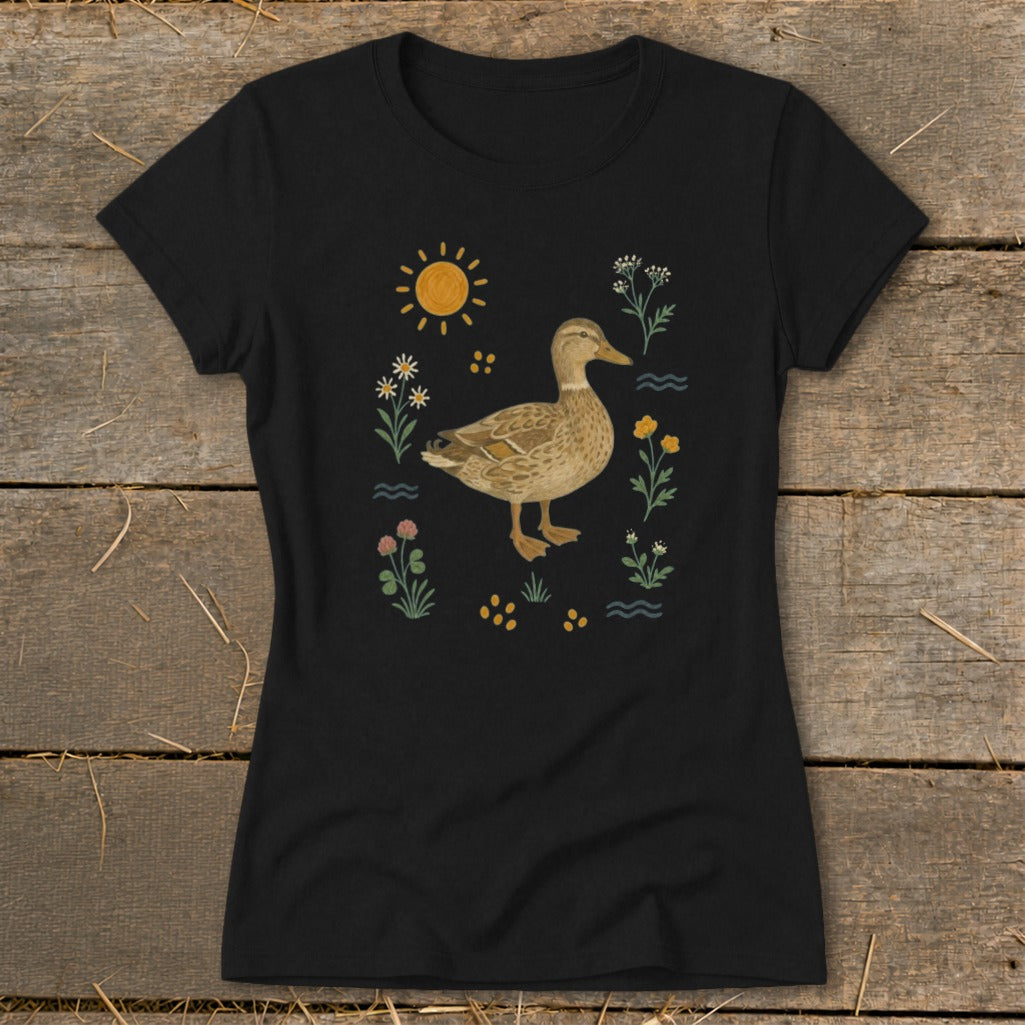 Black t-shirt with a watercolor duck surrounded by flowers and sun.