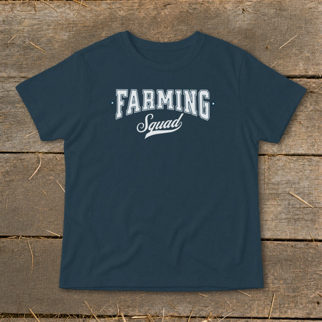 Navy t-shirt with white "FARMING Squad" text, laid on a wooden surface.
