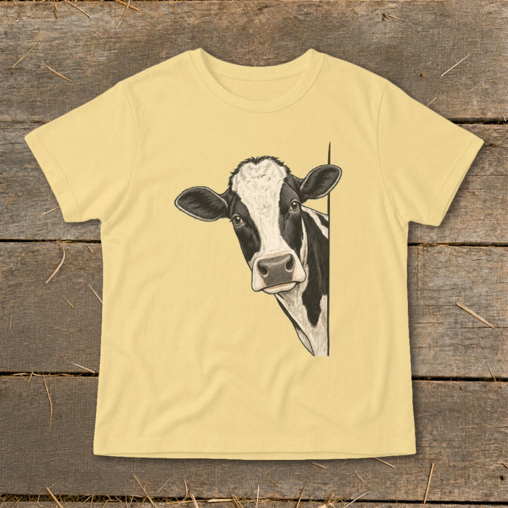 Black and white cow peeking out from behind a pale yellow t-shirt.