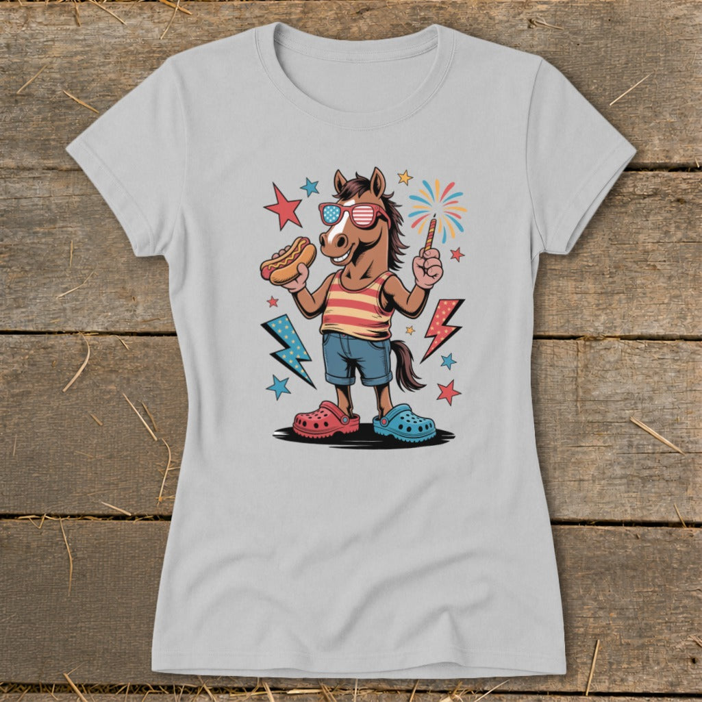 Horse in sunglasses and patriotic shirt holds hot dog and sparkler with fireworks.