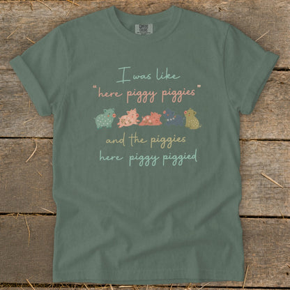 Green t-shirt with "I was like 'here piggy piggies' and the piggies here piggy piggied" and illustration.