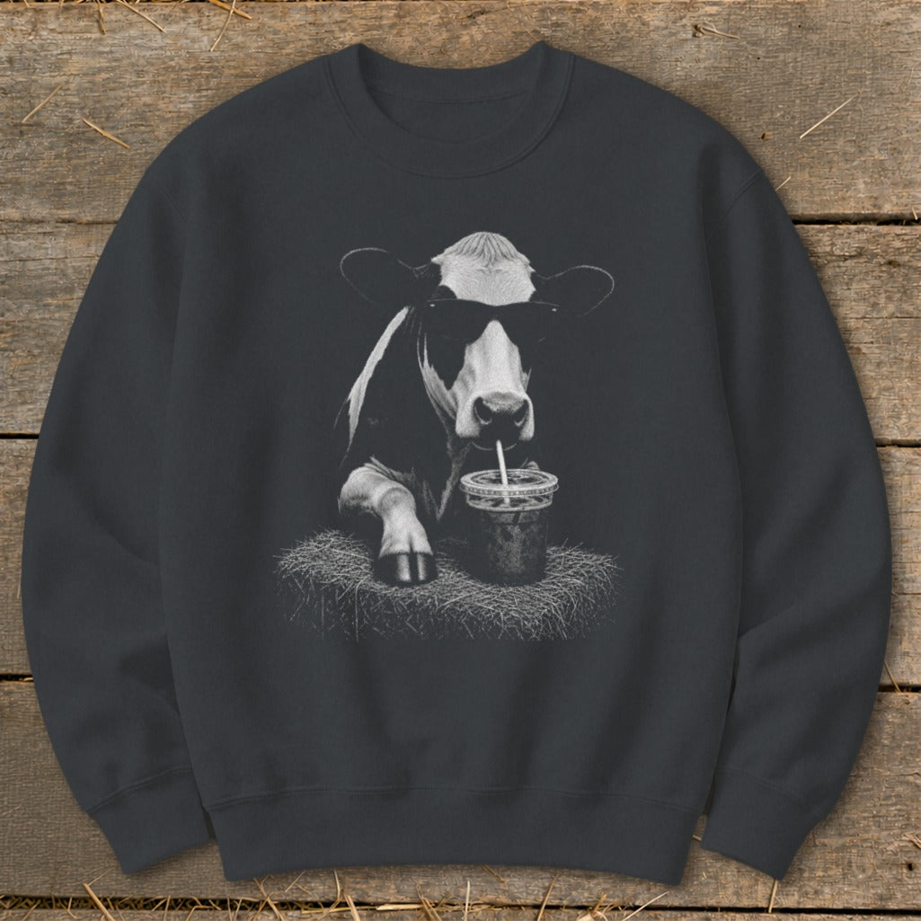 Black and white cow wearing sunglasses drinks from a cup with a straw.