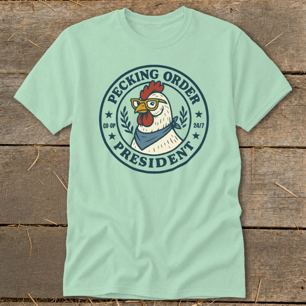 Light blue t-shirt with a cartoon chicken wearing glasses and a bandana, labeled "Pecking Order President".
