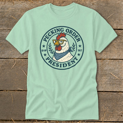Light blue t-shirt with a cartoon chicken wearing glasses and a bandana, labeled "Pecking Order President".