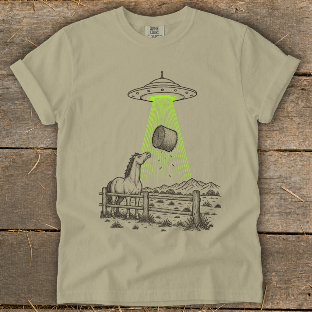 UFO beam abducting hay bale over horse in fenced pasture with mountains.