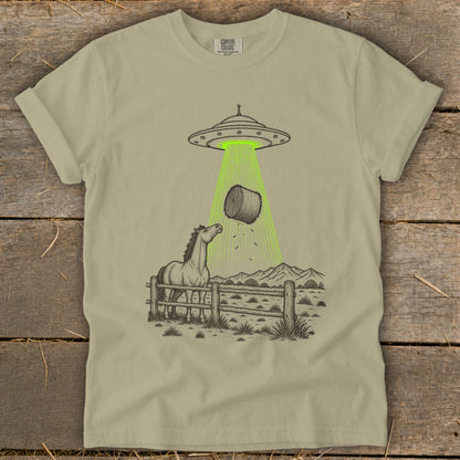 UFO beam abducting hay bale over horse in fenced pasture with mountains.