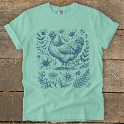 Mint t-shirt with a blue line drawing of a hen surrounded by flowers and leaves.