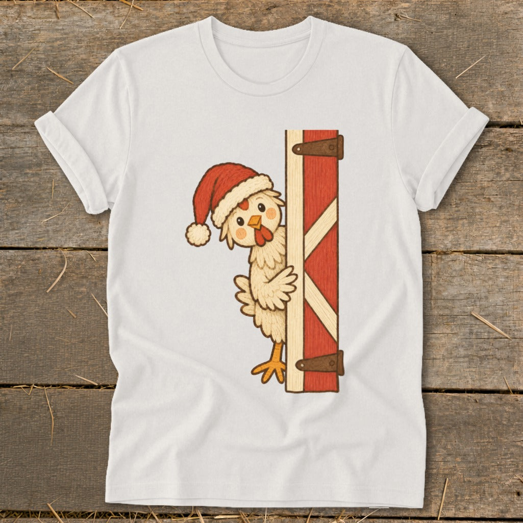 White t-shirt with a cartoon chicken wearing a Santa hat peeking from behind a barn door.