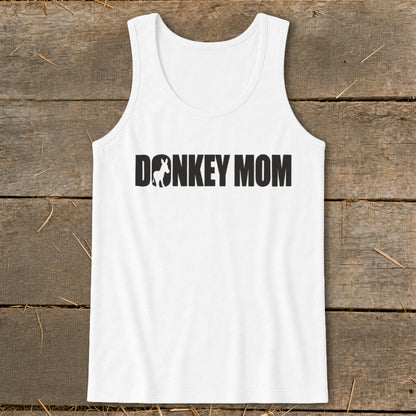 White women's tank top featuring the black text Donkey Mom with a donkey silhouette inside the letter O, displayed on a wooden surface.