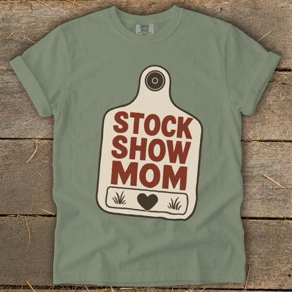 Green t-shirt with "STOCK SHOW MOM" on a tag graphic with a heart.