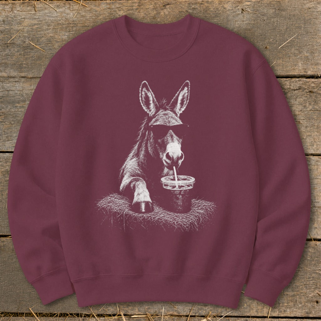 Donkey wearing sunglasses drinks from a cup with a straw on a maroon sweatshirt.