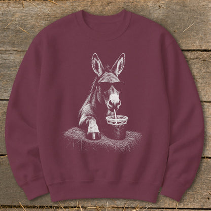 Donkey wearing sunglasses drinks from a cup with a straw on a maroon sweatshirt.