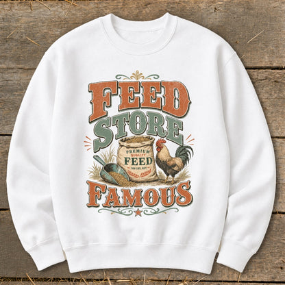White sweatshirt with "FEED STORE FAMOUS" text, bag of feed, scoop, and rooster graphic.