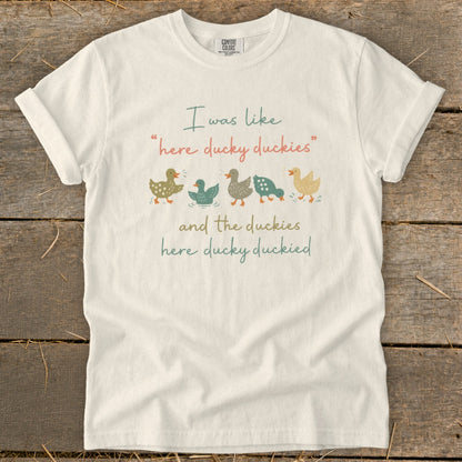 White t-shirt with cartoon ducks and text "I was like 'here ducky duckies' and the duckies here ducky duckied".