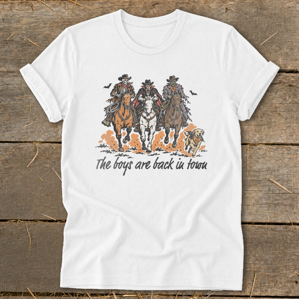 Skeleton, vampire, and zombie cowboys ride horses with a dog, text reads "The boys are back in town".