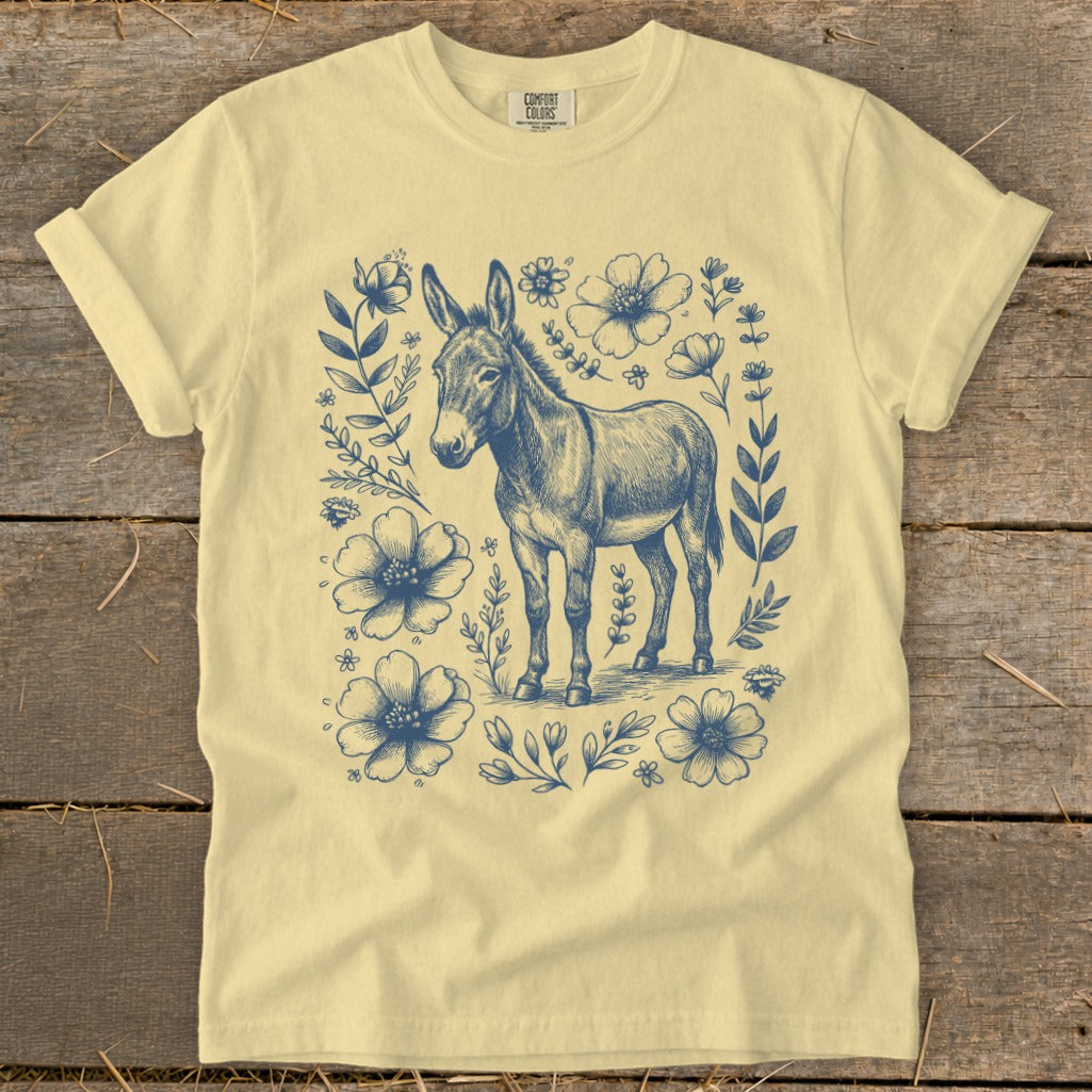 Yellow t-shirt with a vintage-style illustration of a donkey surrounded by blue flowers and foliage.
