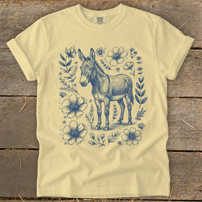 Yellow t-shirt with a vintage-style illustration of a donkey surrounded by blue flowers and foliage.