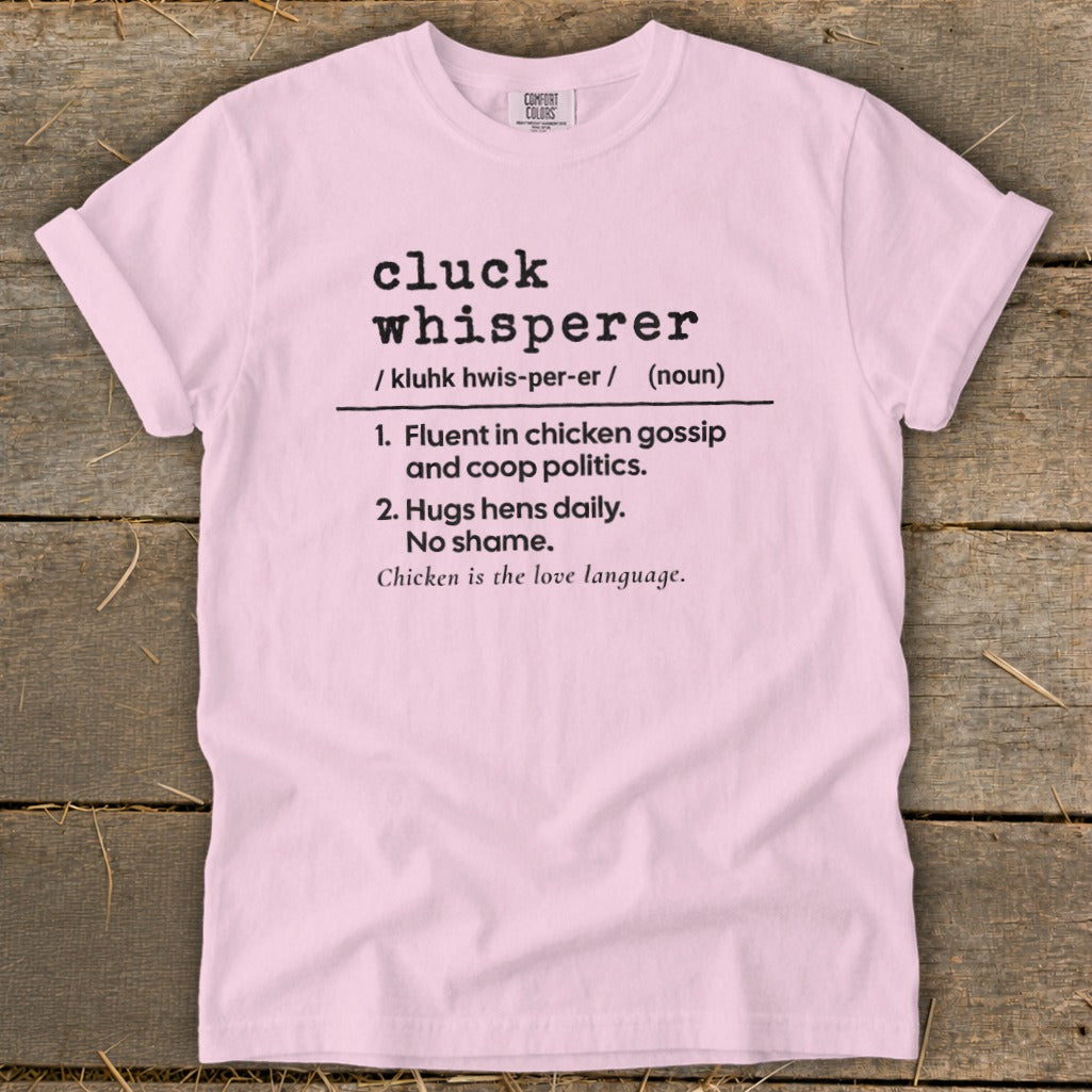 Pink t-shirt with "cluck whisperer" definition in black text.