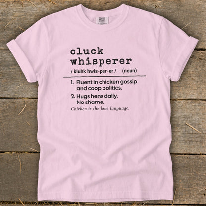 Pink t-shirt with "cluck whisperer" definition in black text.