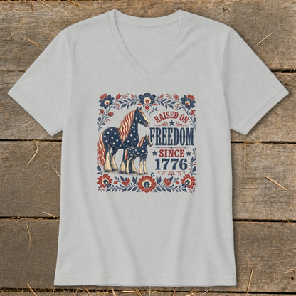 T-shirt graphic featuring two horses with American flag patterns and text "Raised on Freedom Since 1776".