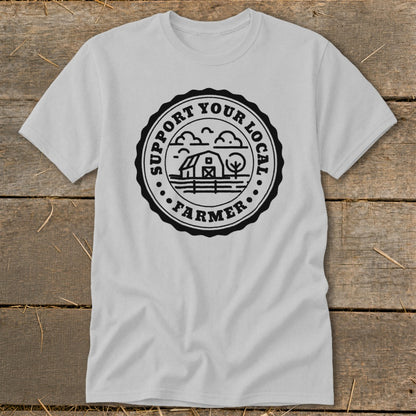 Gray t-shirt with a circular black graphic featuring a barn, tree, and clouds. Text reads "Support Your Local Farmer."