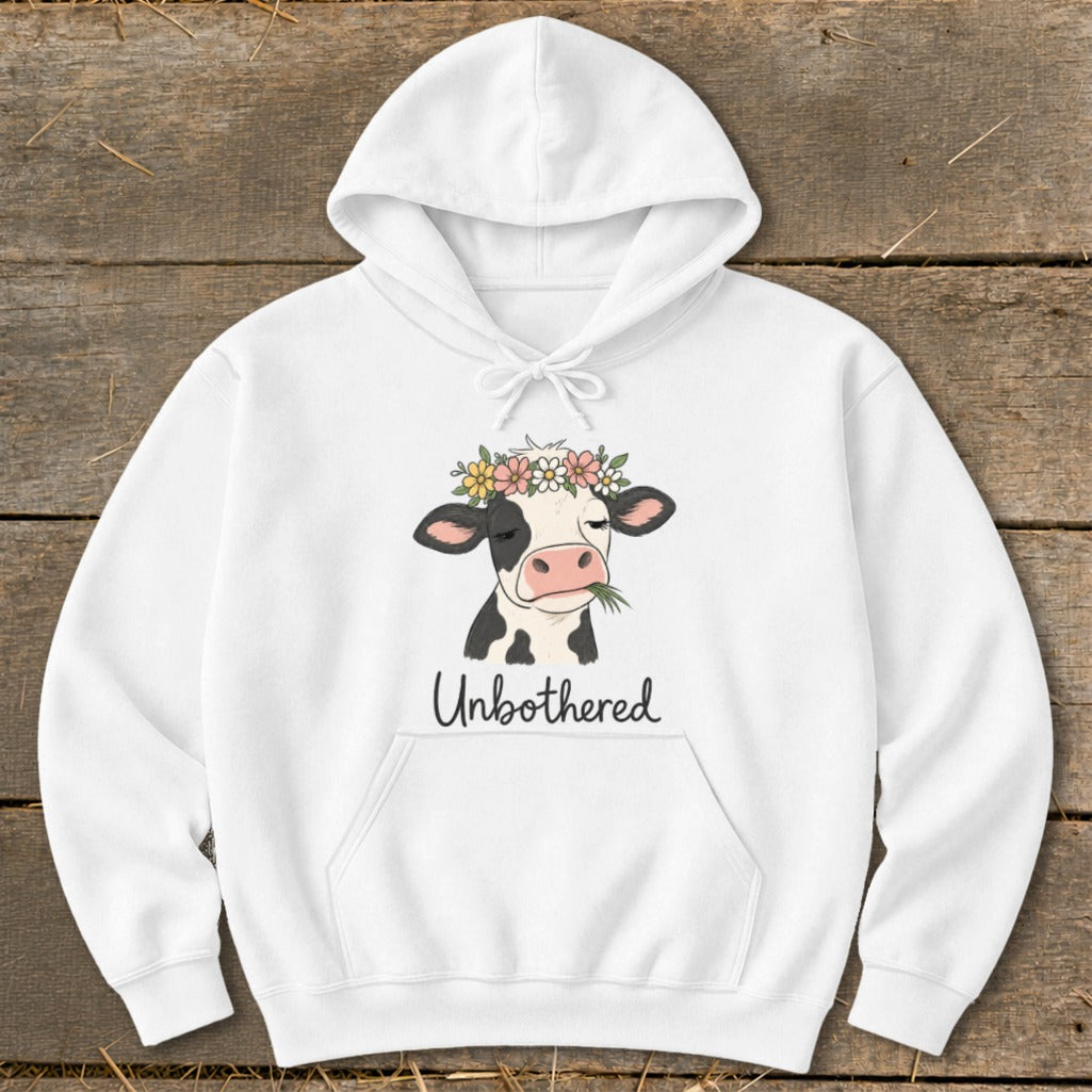 White hoodie with a cartoon cow wearing a flower crown and the text "Unbothered".
