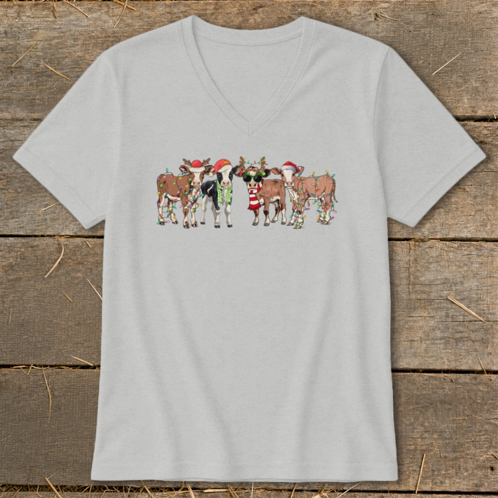 Christmas cows wearing Santa hats and scarves with festive lights.
