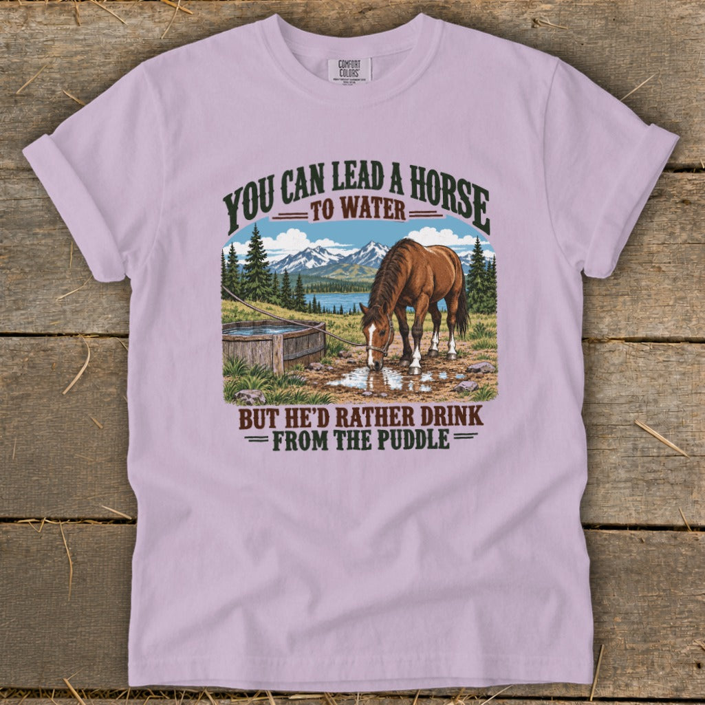 A light purple t-shirt featuring a graphic of a horse drinking from a puddle.