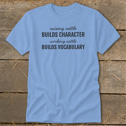 Light blue t-shirt with black text: "raising cattle BUILDS CHARACTER, working cattle BUILDS VOCABULARY."