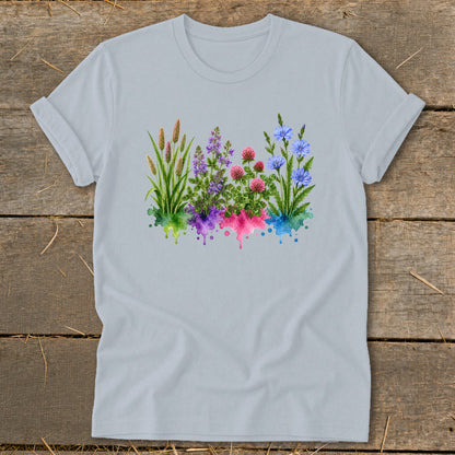 A light gray t-shirt featuring a watercolor graphic of colorful wildflowers and grasses on a wooden surface.