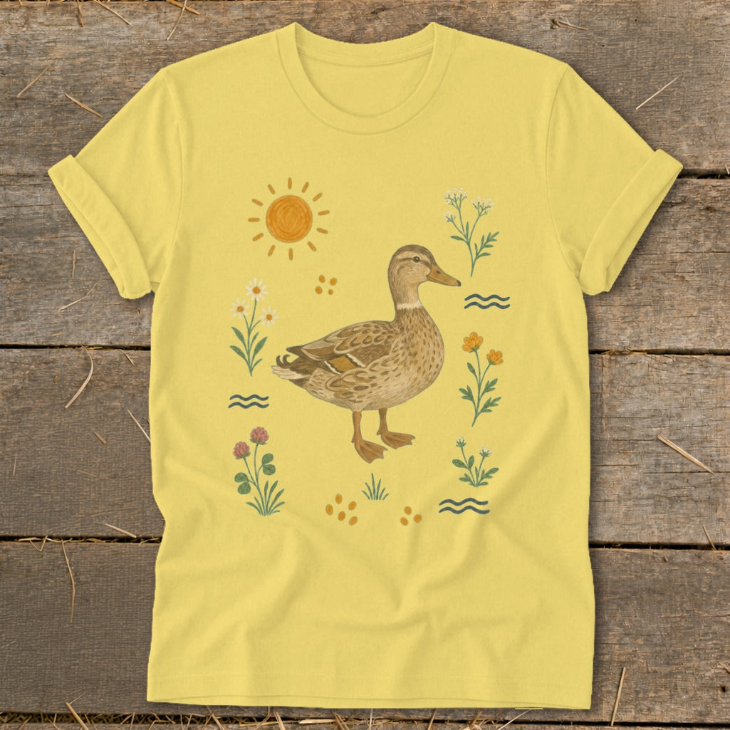 Yellow t-shirt with a duck illustration surrounded by flowers, sun, and water waves.