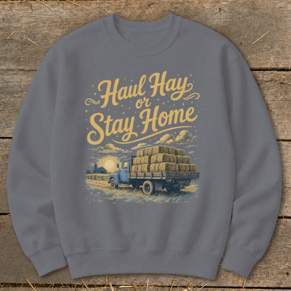 Sweatshirt with yellow text "Haul Hay or Stay Home" and illustration of a truck carrying hay bales.