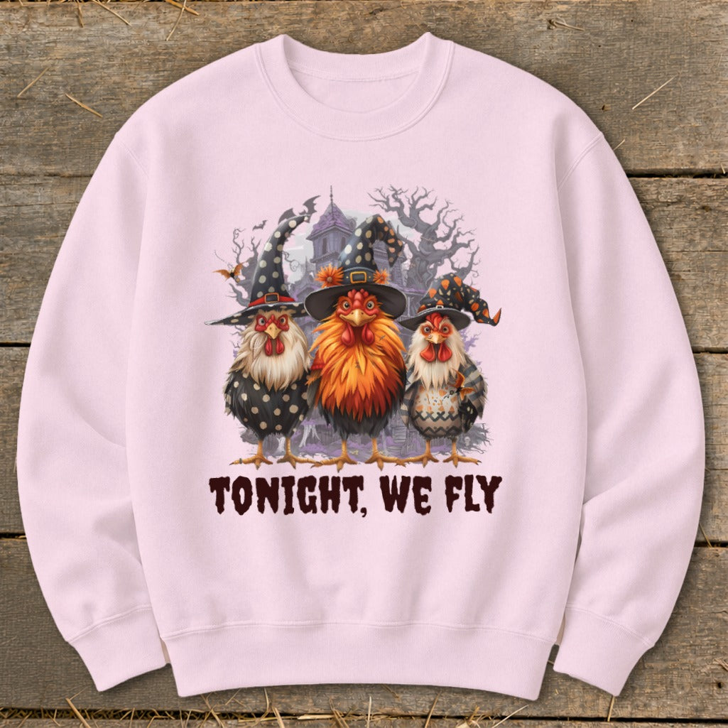 Three chickens in witch hats and Halloween costumes stand before a spooky mansion.