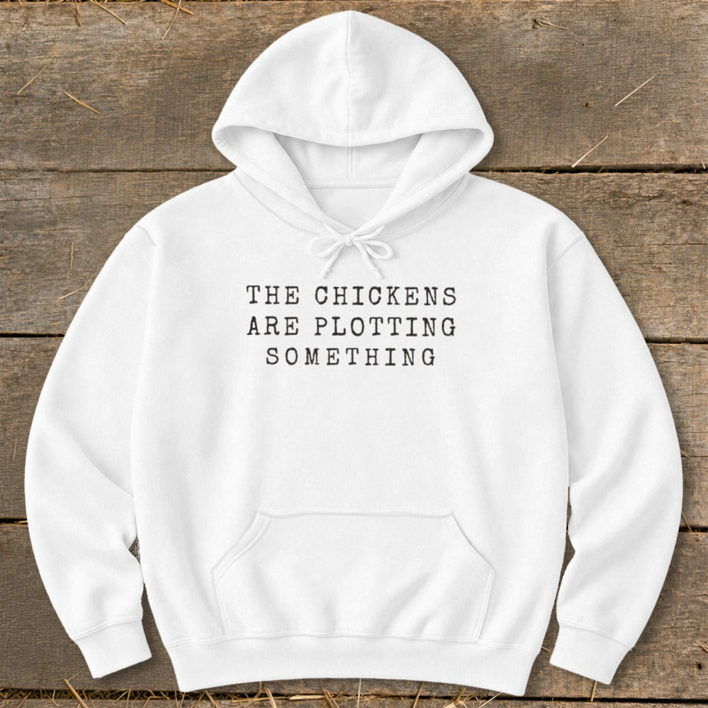 White hooded sweatshirt with black text that reads "THE CHICKENS ARE PLOTTING SOMETHING".