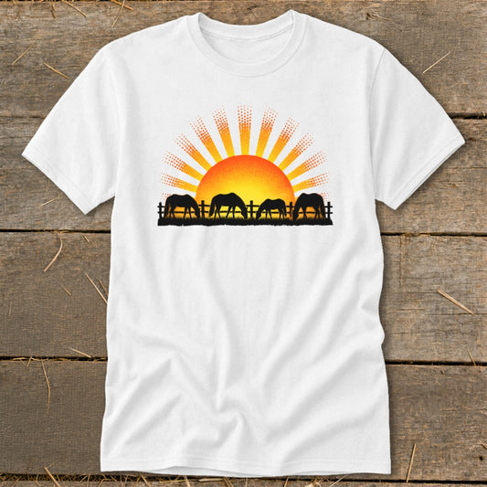 Four horses graze in silhouette against a sunset on a white t-shirt.