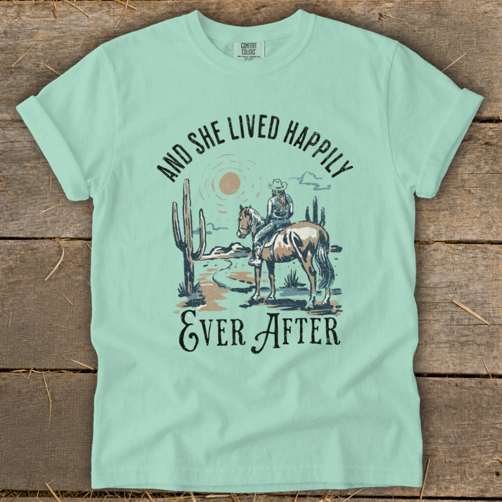 Light blue t-shirt with a desert scene and the text "AND SHE LIVED HAPPILY EVER AFTER".